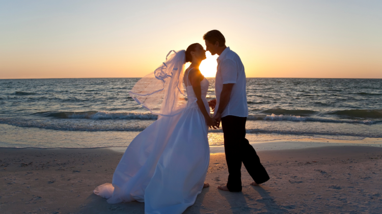 wedding on the beach with bride and groom at sunset