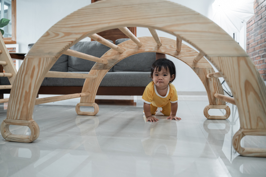 baby crawling through wooden structure