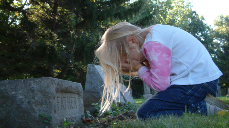 child grieving at gravesite