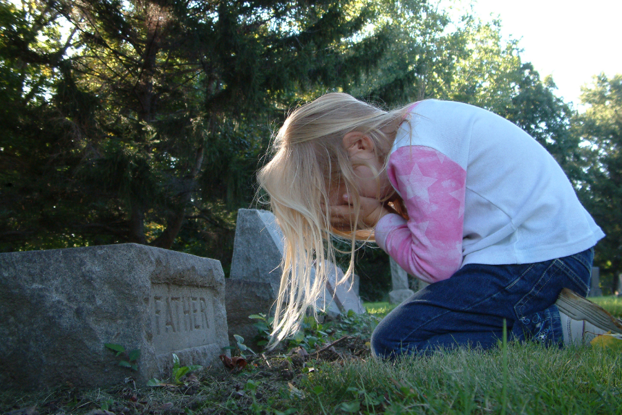 child grieving at gravesite
