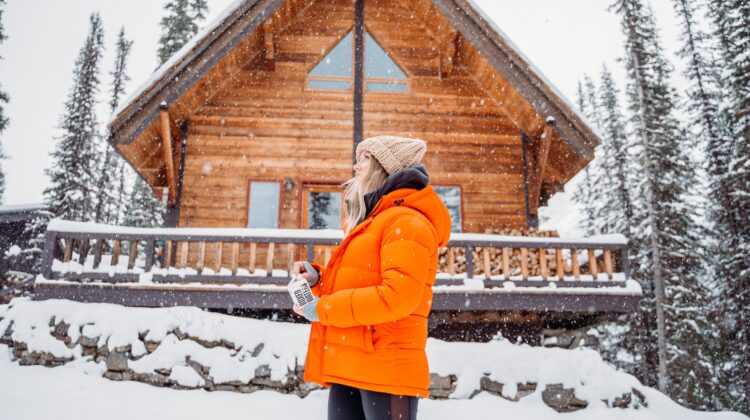 cabin home in winter with woman outside