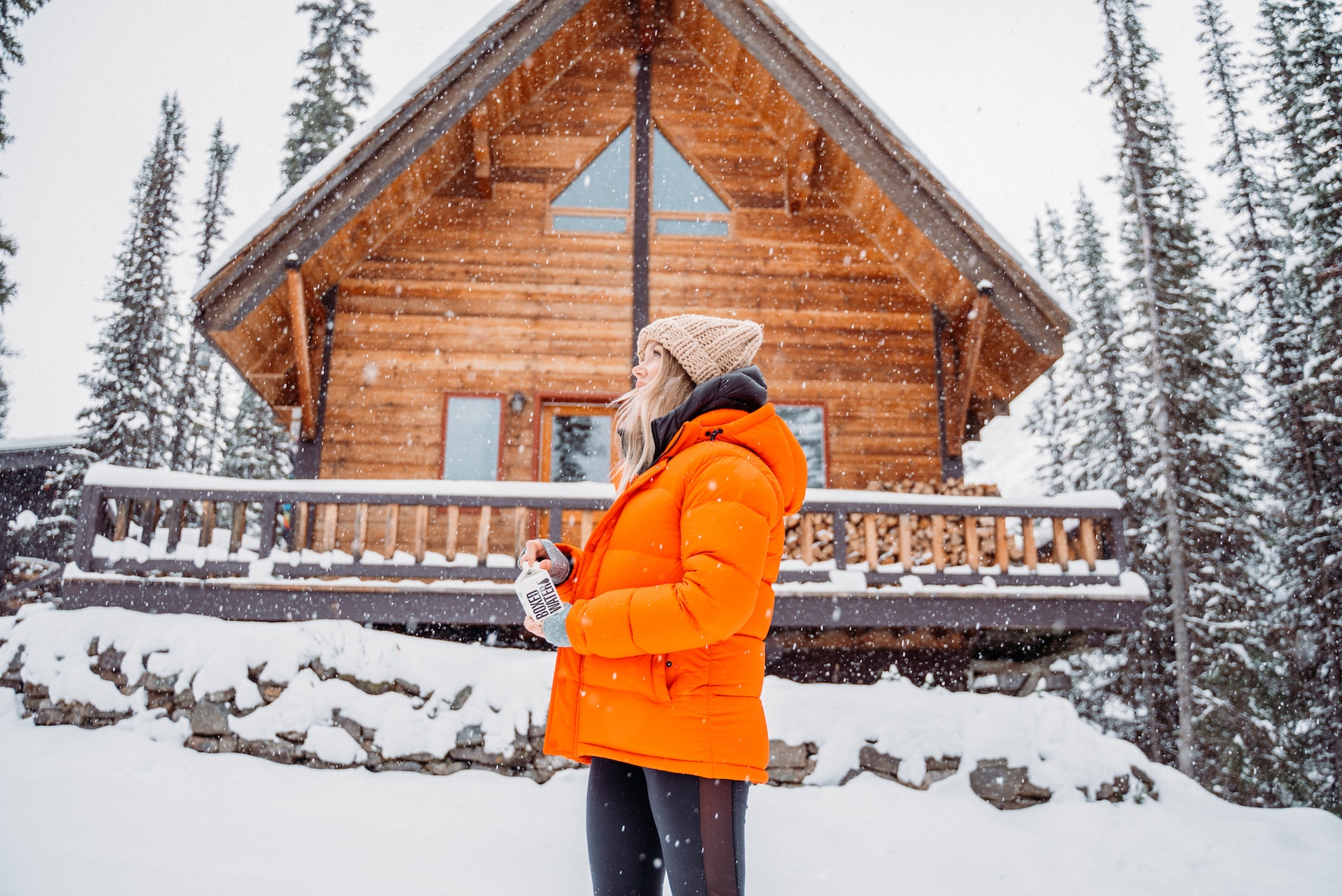 cabin home in winter with woman outside