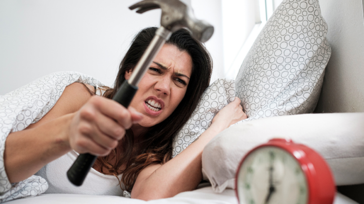 woman with hammer trying to hit alarm clock