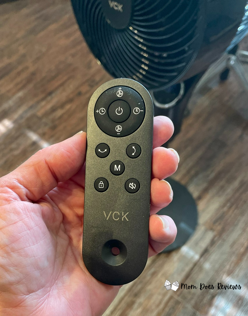 A VCK pedestal fan remote in a hand.