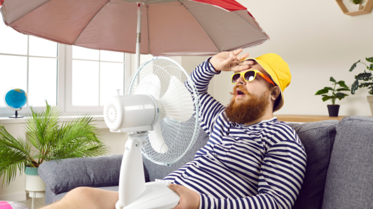 man outside with fan and umbrella in summertime heat