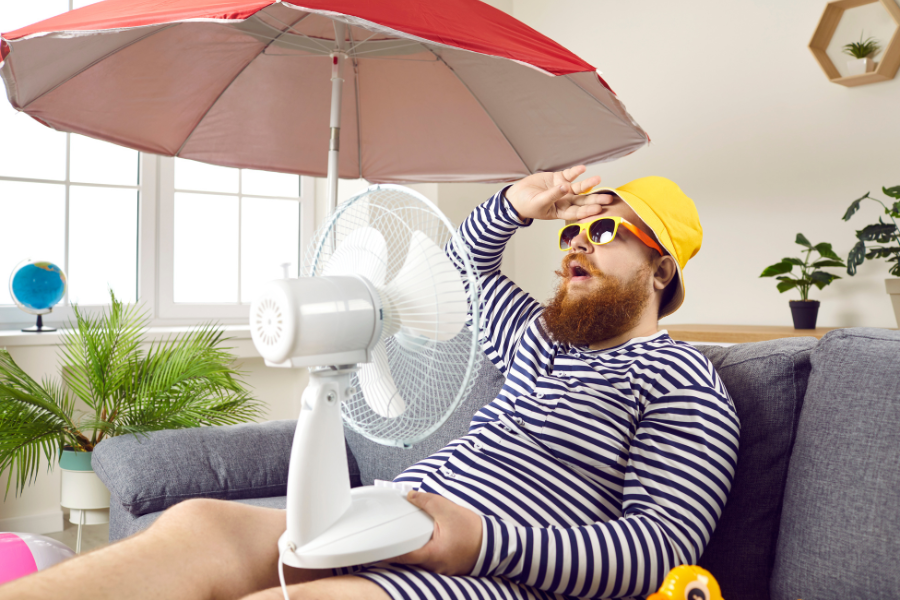 man outside with fan and umbrella in summertime heat