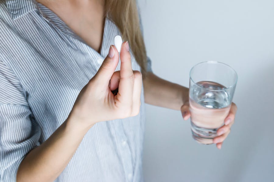 woman holding pill to swallow
