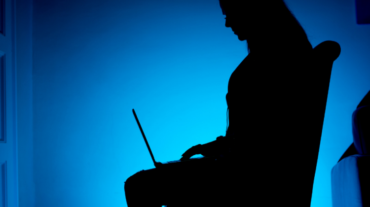 anonymous figure using laptop