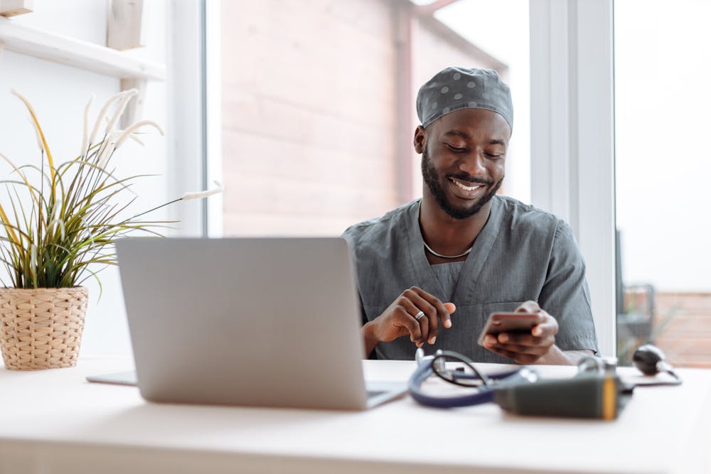 man wearing scrubs with laptop