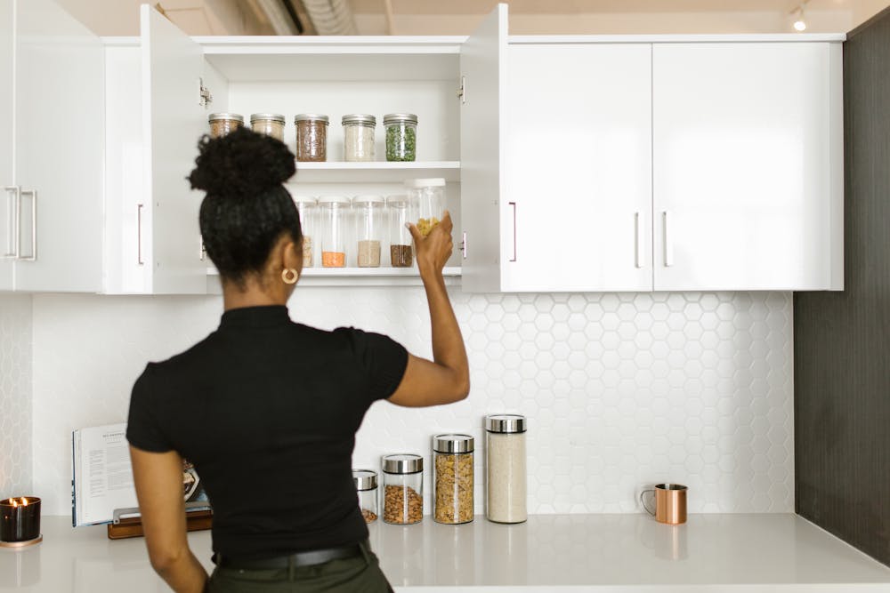 A woman arranging a kitchen cabinet.