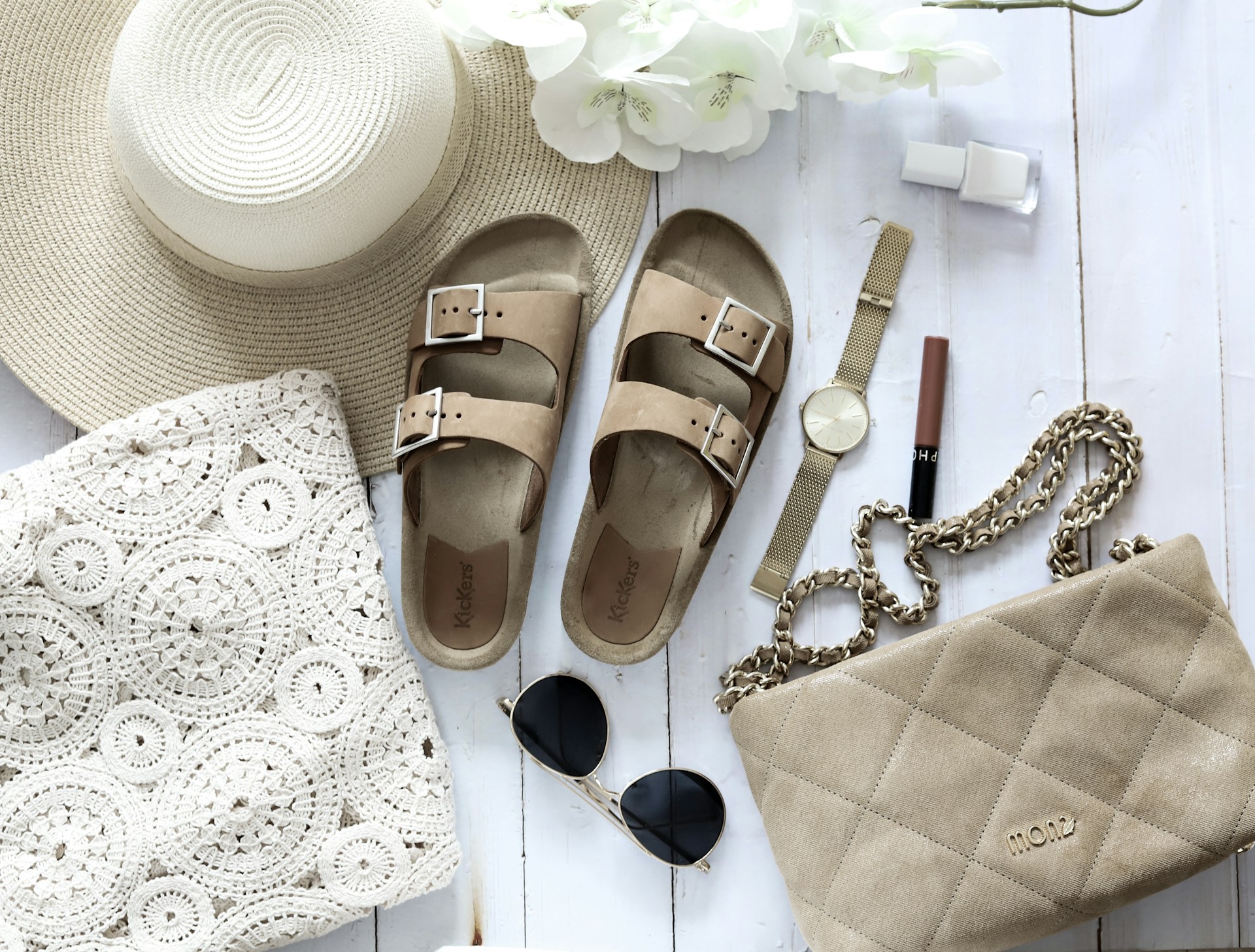 Flat lay of a brunch outfit with a midi dress, sandals, and a straw bag