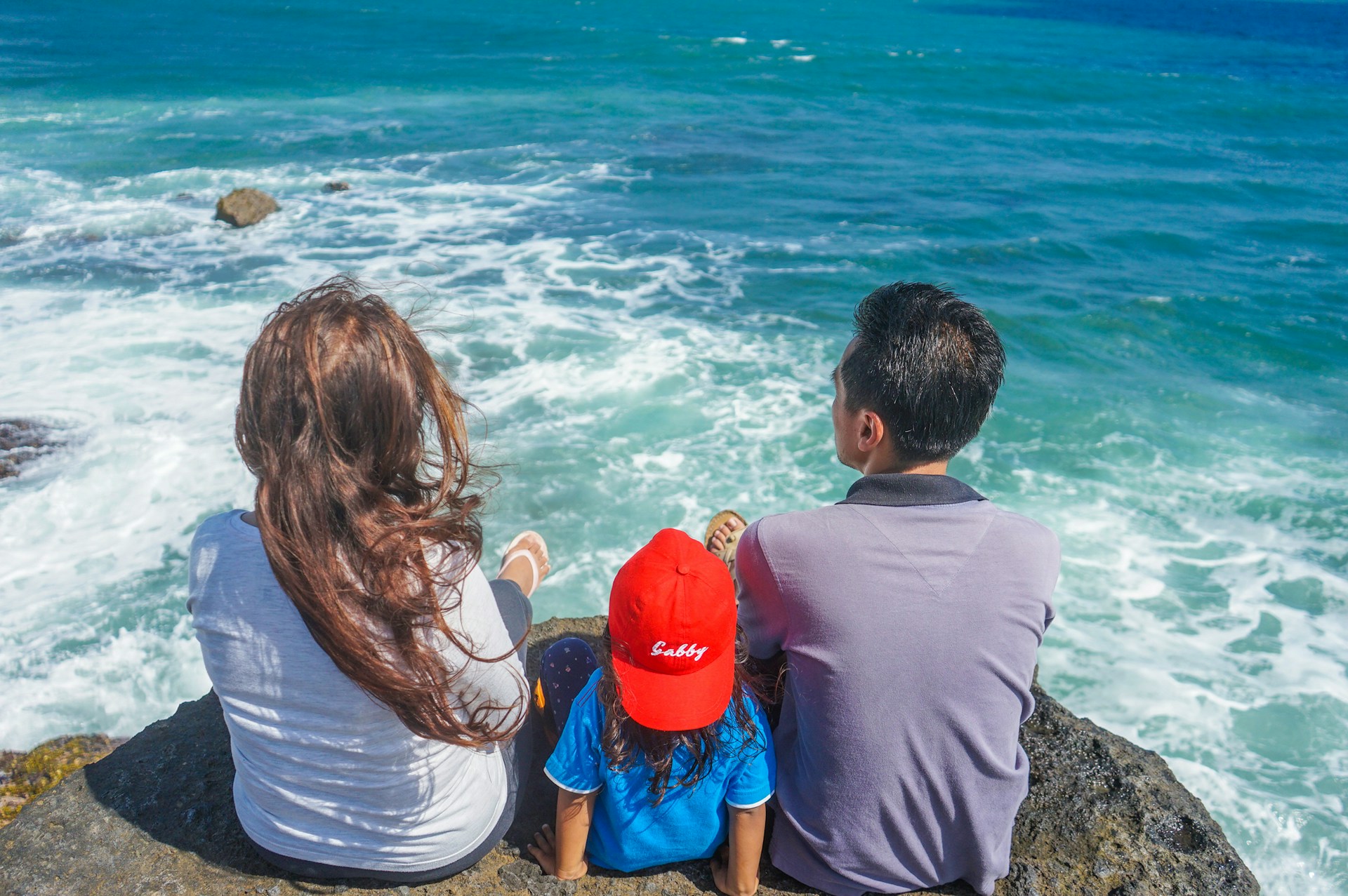 family sitting on a rock at ocean adventures