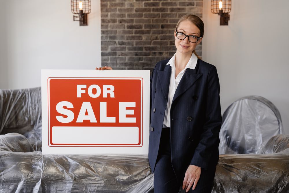 woman holding for sale sign