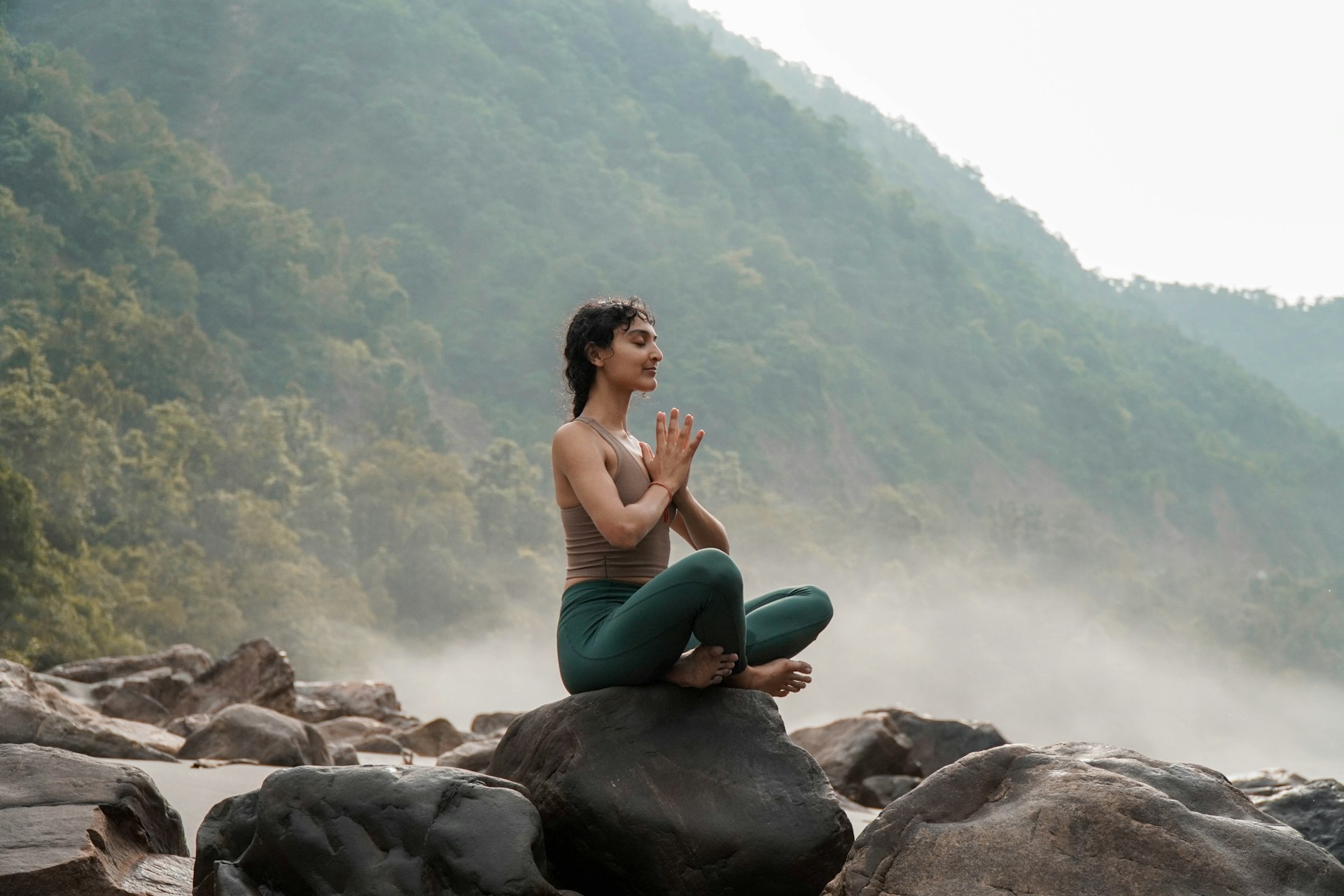 woman sitting in meditation on rock
