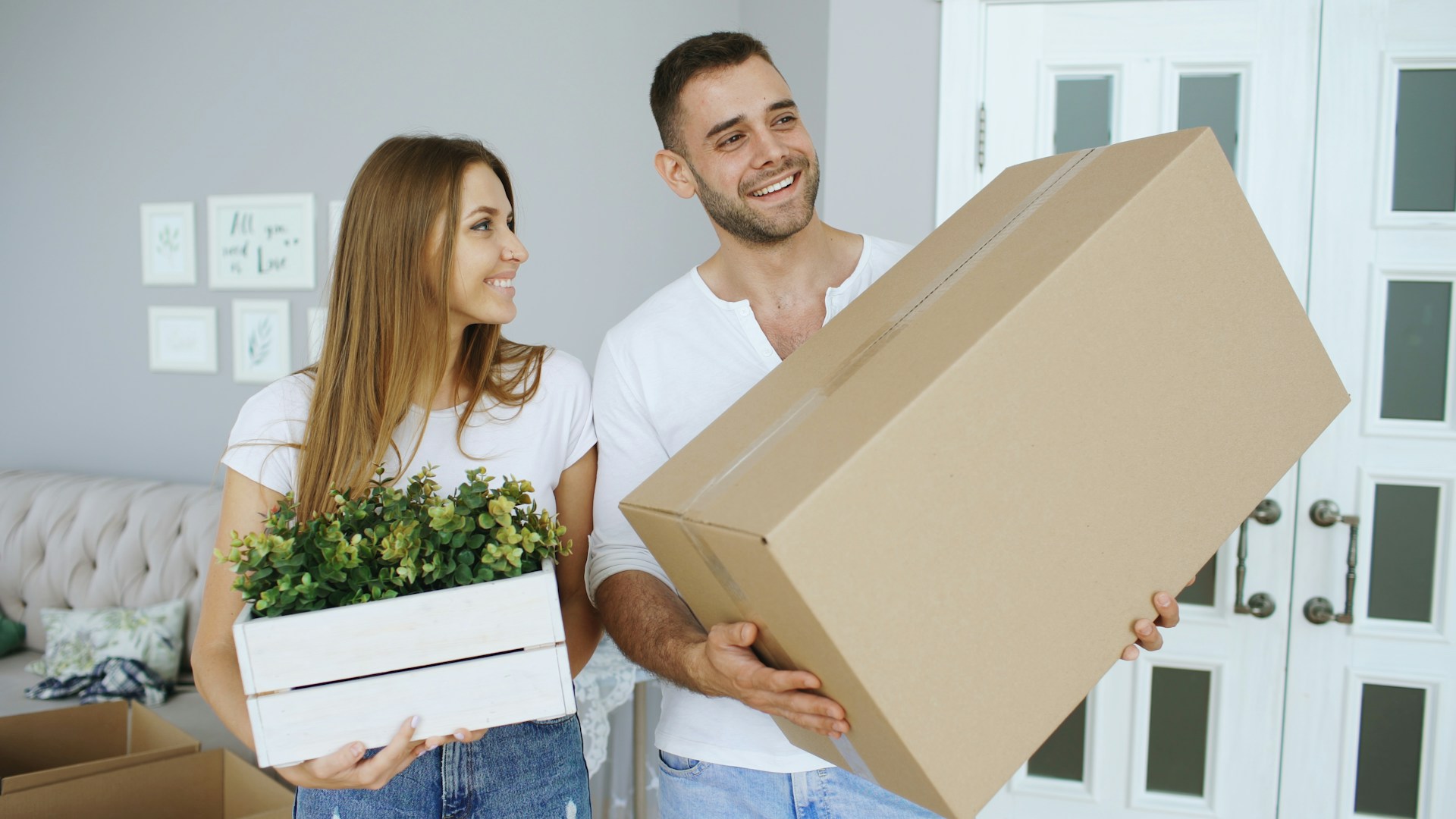 couple carrying boxes and plant