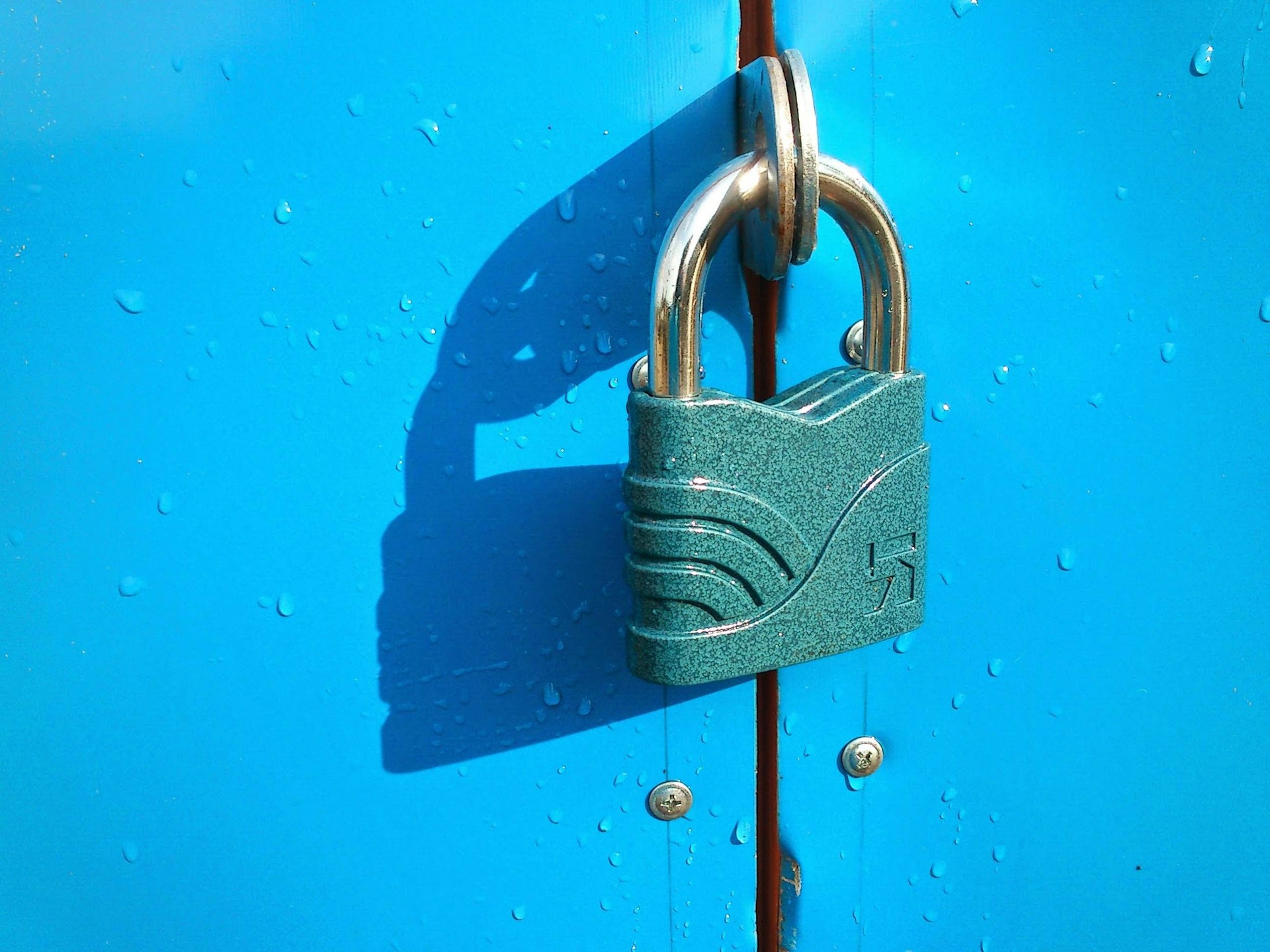 A green padlock securing the doors of a blue metal cabinet